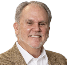 A smiling man in a tan jacket.