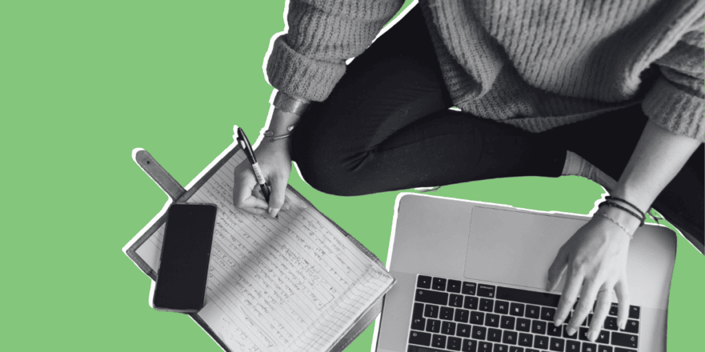 A person sits cross-legged, writing in a notebook with a pen while using a laptop; a smartphone rests on the open notebook. The background is a solid green.